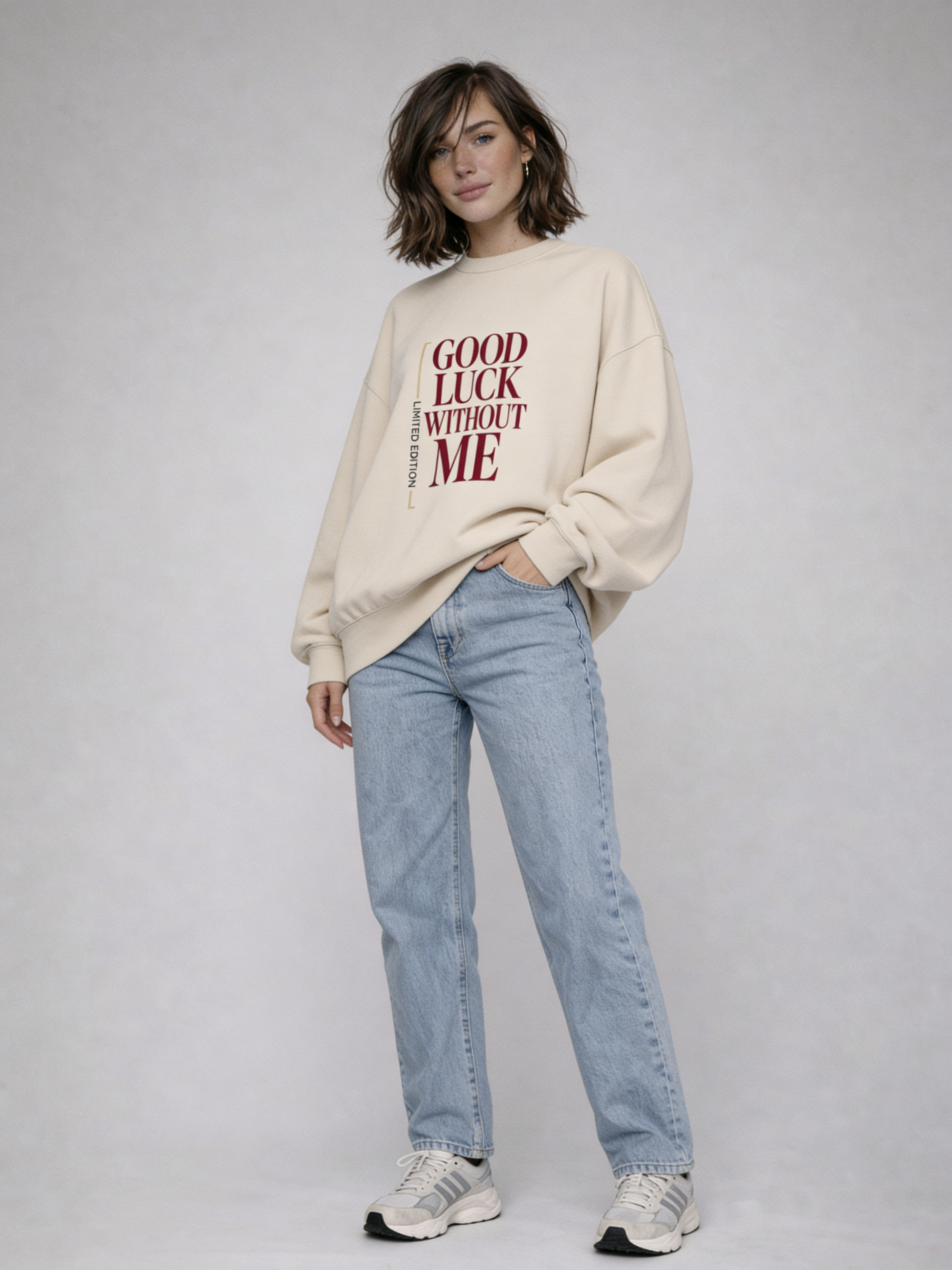 Female model wearing beige oversized Noiré sweatshirt with “Good Luck Without Me” print, full-body front view, streetwear styling.