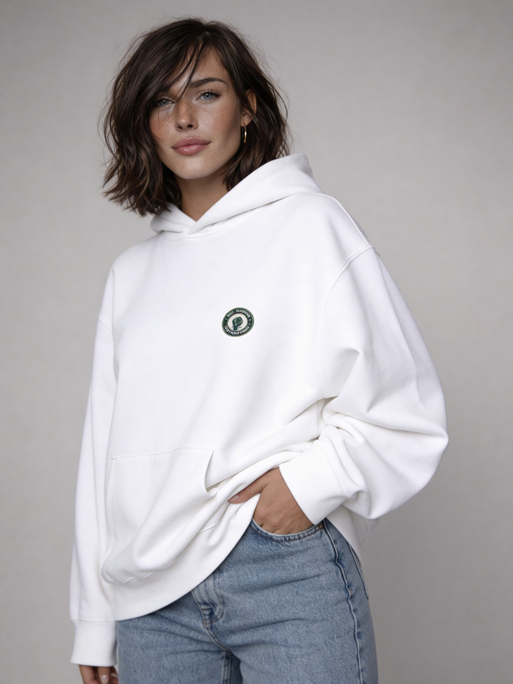 White oversized hoodie front view on female model wearing light blue jeans, minimal streetwear style