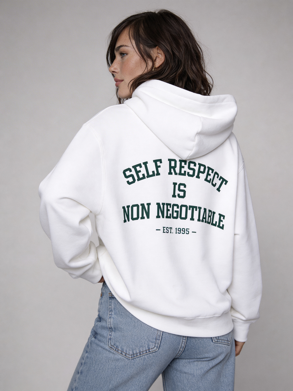 White oversized hoodie back view on female model with green “Self Respect Is Non Negotiable – EST. 1995” print, streetwear design