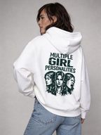 Female model wearing oversized white hoodie featuring “Multiple Girl Personalities” back print graphic, styled with blue denim jeans, women’s streetwear fashion photography.
