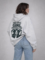 Woman wearing oversized light grey hoodie with “Multiple Girl Personalities” graphic print on the back, paired with light blue jeans, streetwear fashion model shot for online store.