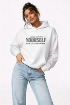 female model relaxed pose wearing oversized white graphic hoodie compare yourself quote streetwear outfit