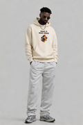 male model looking down wearing oversized beige hoodie with cube graphic print urban streetwear fashion look