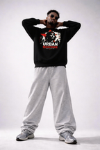 male model standing hands behind head wearing black oversized graphic sweatshirt urban resistance design relaxed streetwear style