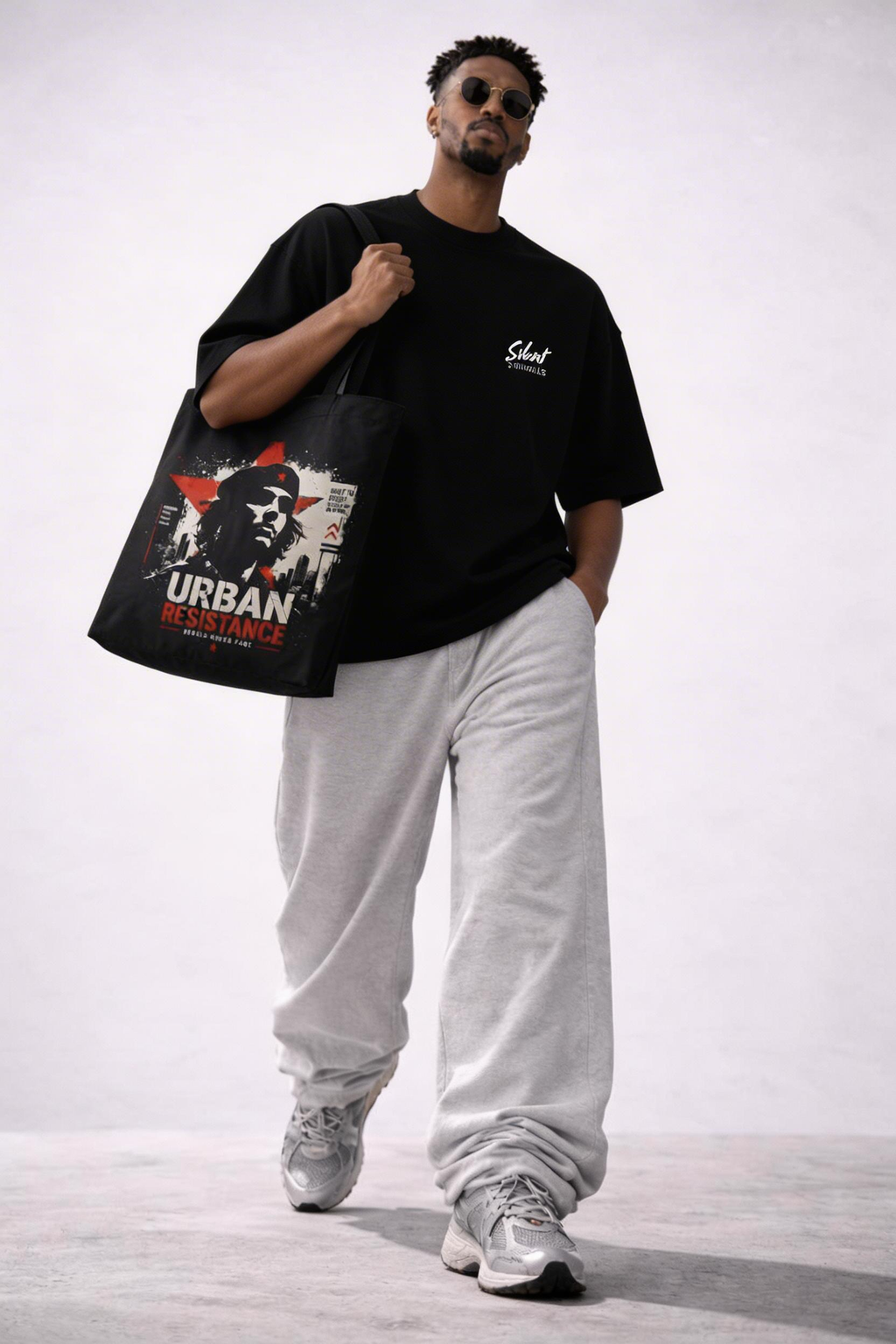 male model side view carrying black tote bag urban resistance artwork urban streetwear look