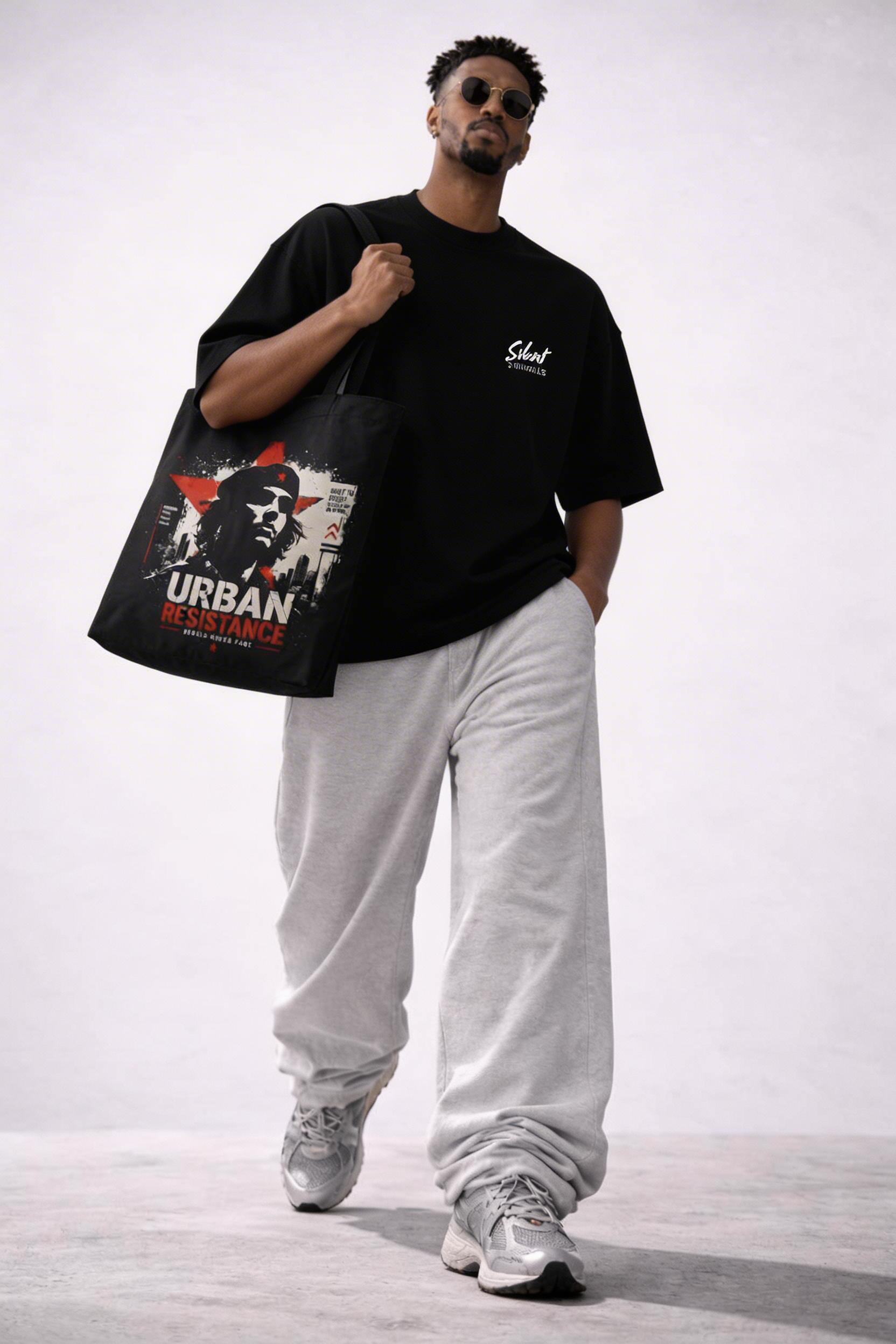 male model side view carrying black tote bag urban resistance artwork urban streetwear look