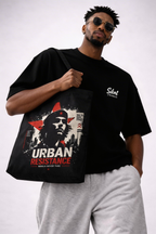 male model close up holding tote bag urban resistance design detail streetwear fashion