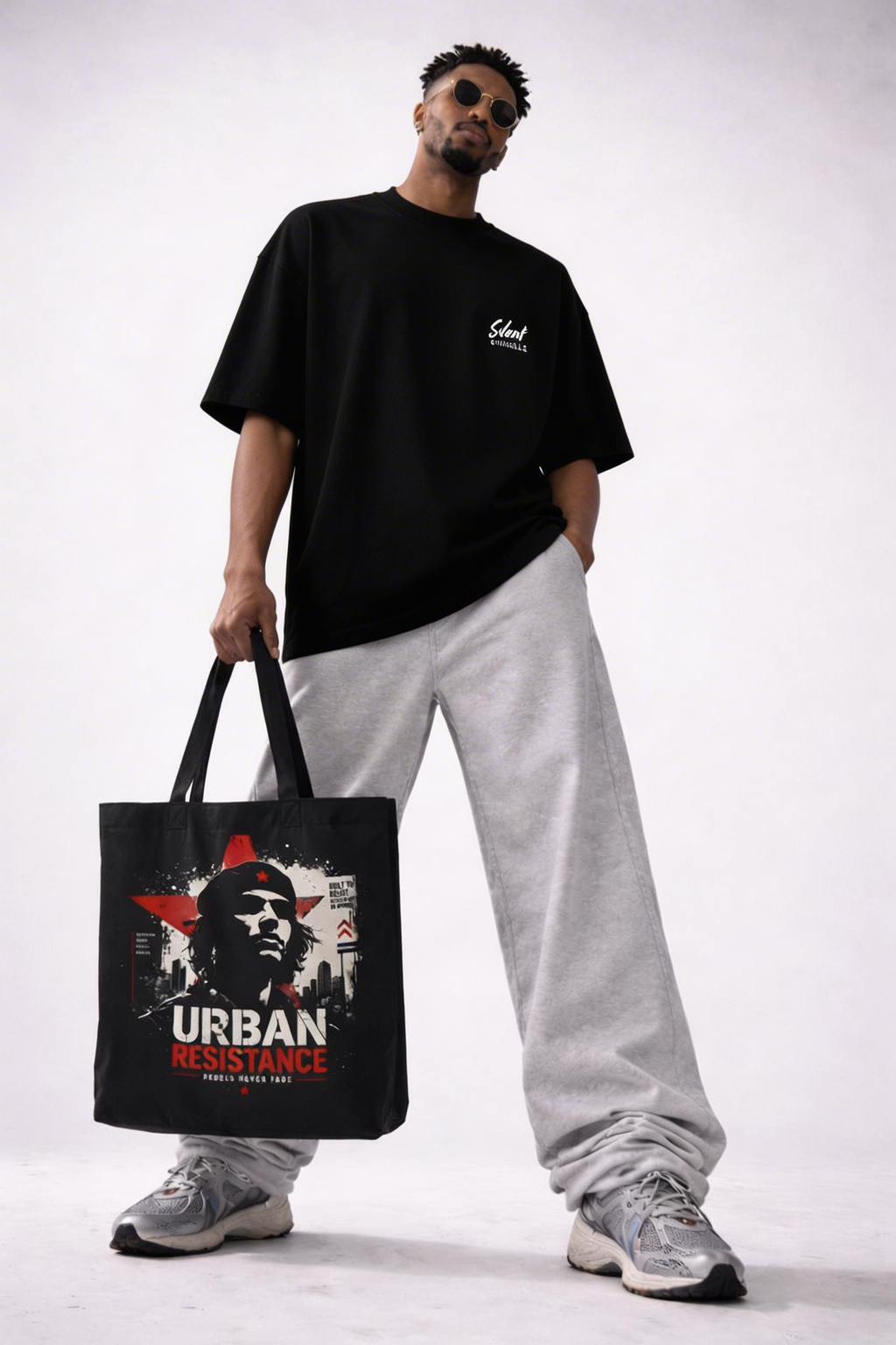 male model front view holding black tote bag urban resistance design streetwear outfit