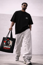 male model side view carrying black tote bag urban resistance artwork urban streetwear look