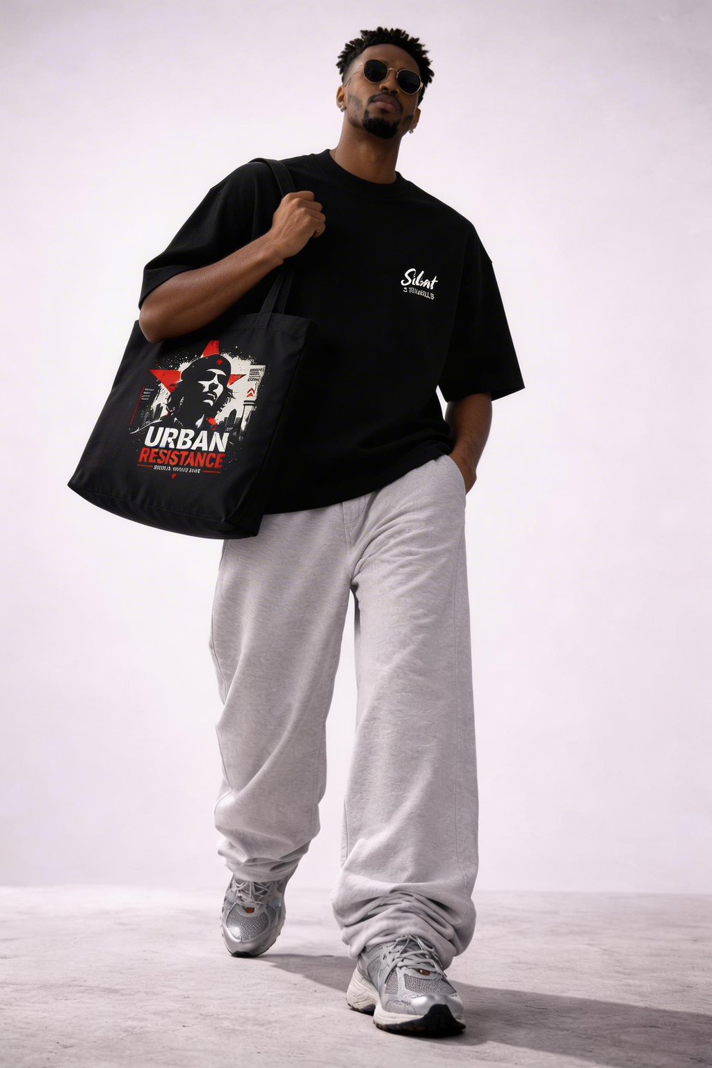 male model walking holding black graphic tote bag urban resistance print casual streetwear style