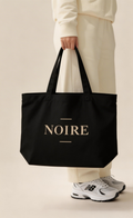 model hand holding black oversized eco tote bag NOIRE logo minimal streetwear style urban fashion accessory