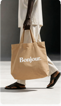 model walking holding beige tote bag bonjour typography design urban streetwear outfit