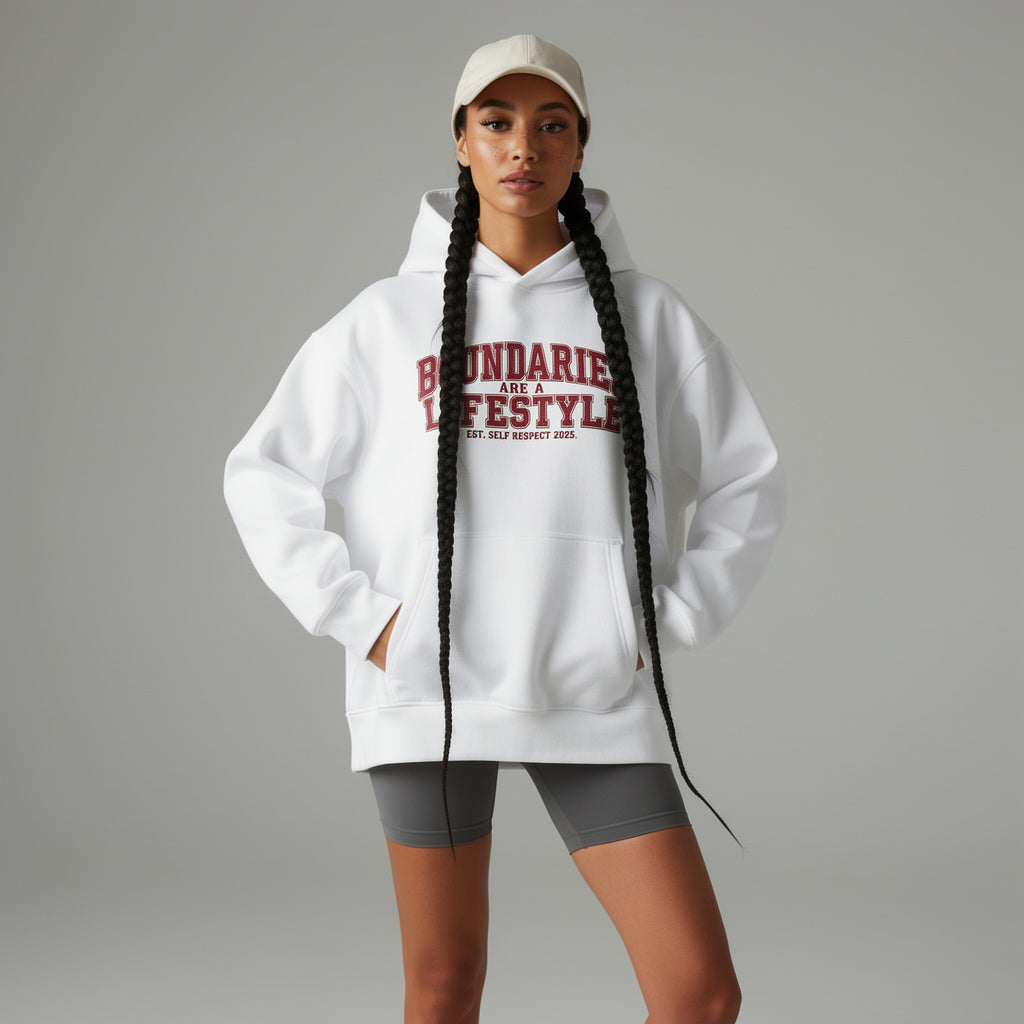 Model wearing white unisex hoodie with “Boundaries Are a Lifestyle” text design in a clean studio setting