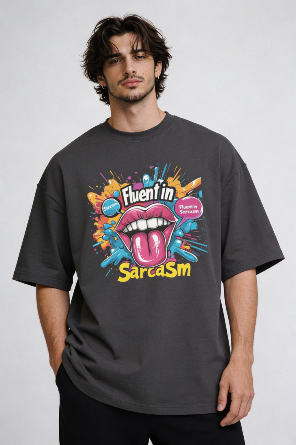 Male model wearing oversized dark gray “Fluent in Sarcasm” t-shirt with bold multicolor graphic print and casual streetwear styling.