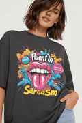 Close-up of oversized dark gray “Fluent in Sarcasm” graphic t-shirt showing detailed pop art lips illustration and vibrant typography.