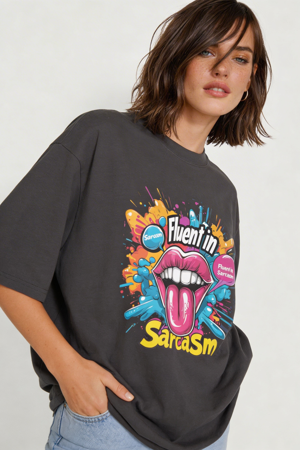 Female model wearing oversized dark gray “Fluent in Sarcasm” graphic t-shirt with colorful pop art lips design and relaxed streetwear fit.