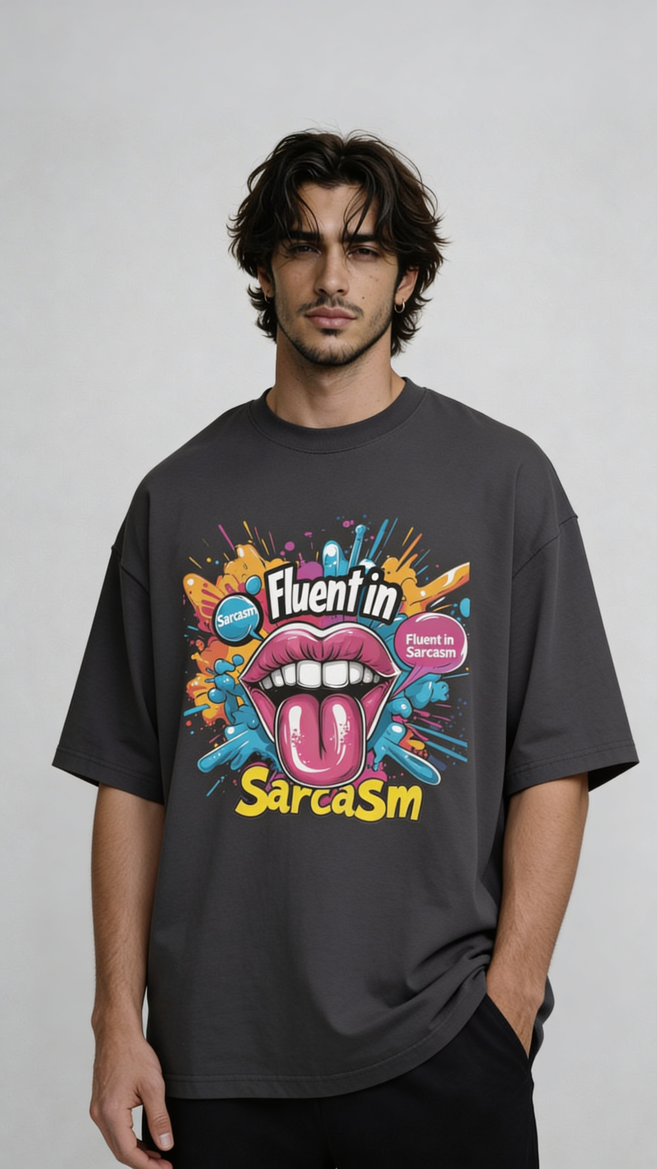 Male model wearing oversized dark gray “Fluent in Sarcasm” t-shirt with bold multicolor graphic print and casual streetwear styling.