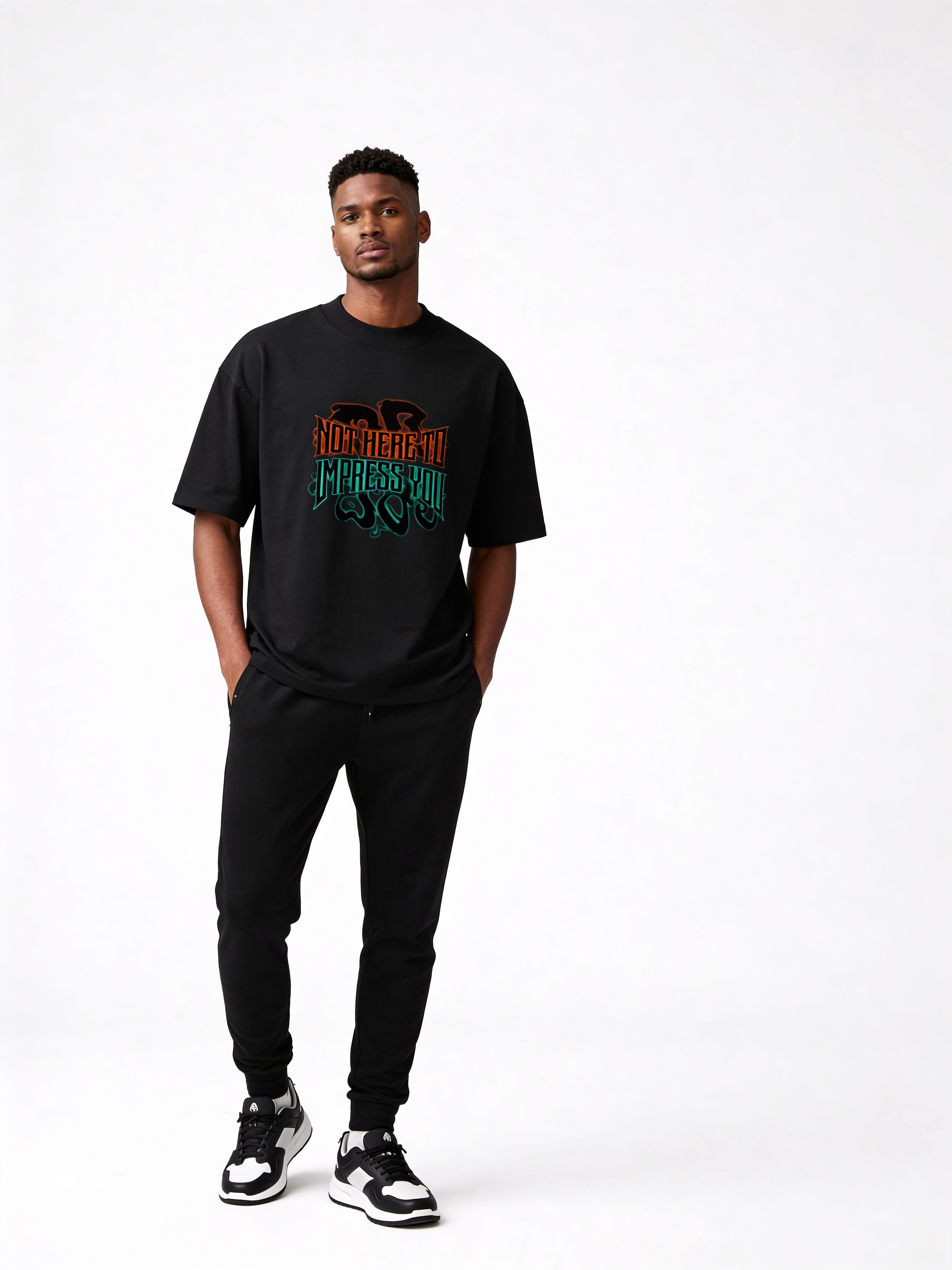 Black oversized graphic t-shirt featuring “Not Here to Impress You” statement design worn by male model, minimalist studio background.