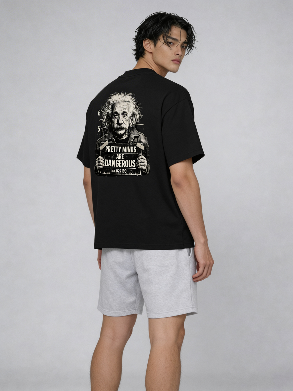 Fashion model posing in black oversized graphic t-shirt with Albert Einstein back artwork and “Pretty Minds Are Dangerous” typography, styled with grey shorts for urban streetwear aesthetic
