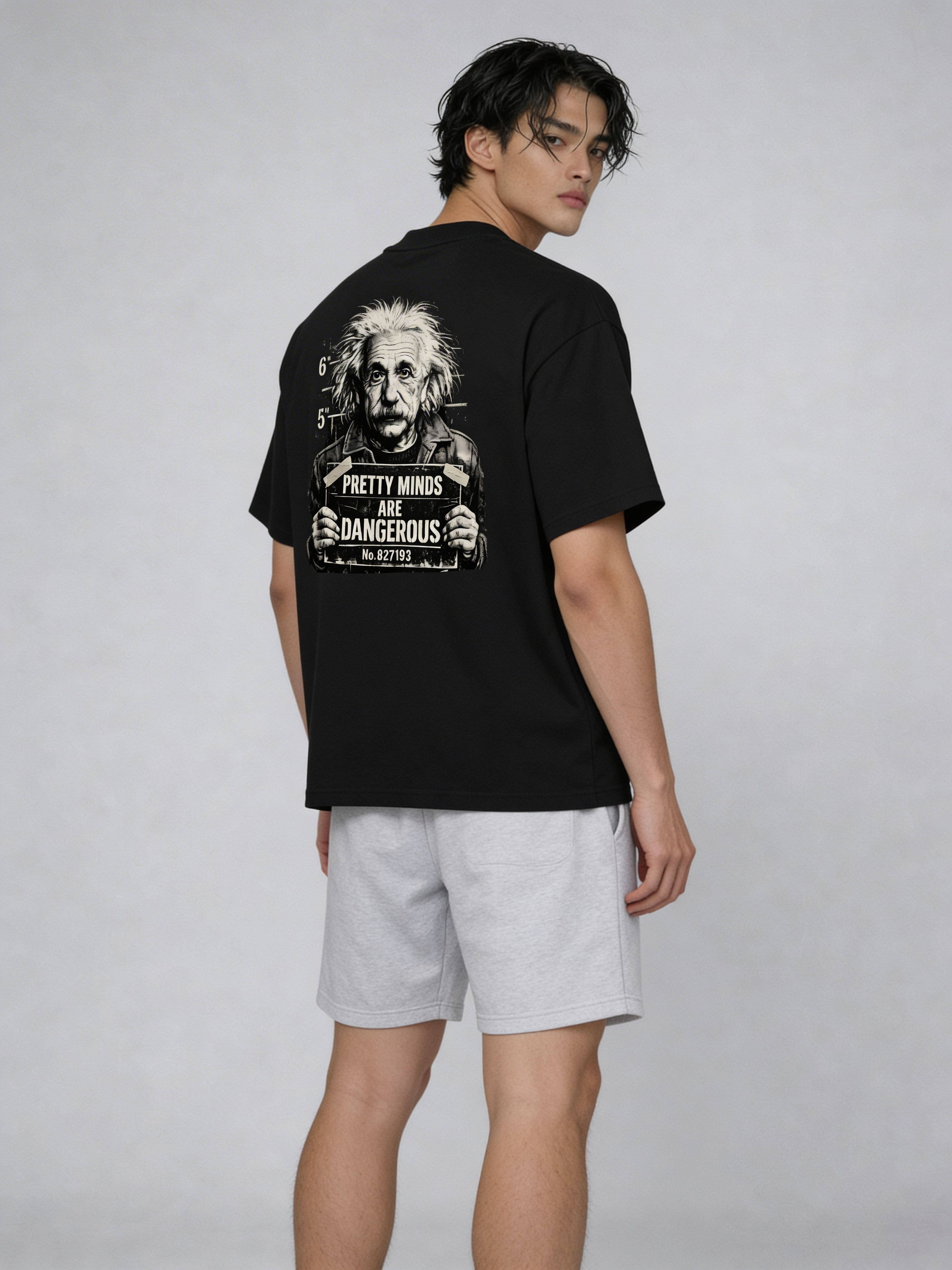 Fashion model posing in black oversized graphic t-shirt with Albert Einstein back artwork and “Pretty Minds Are Dangerous” typography, styled with grey shorts for urban streetwear aesthetic