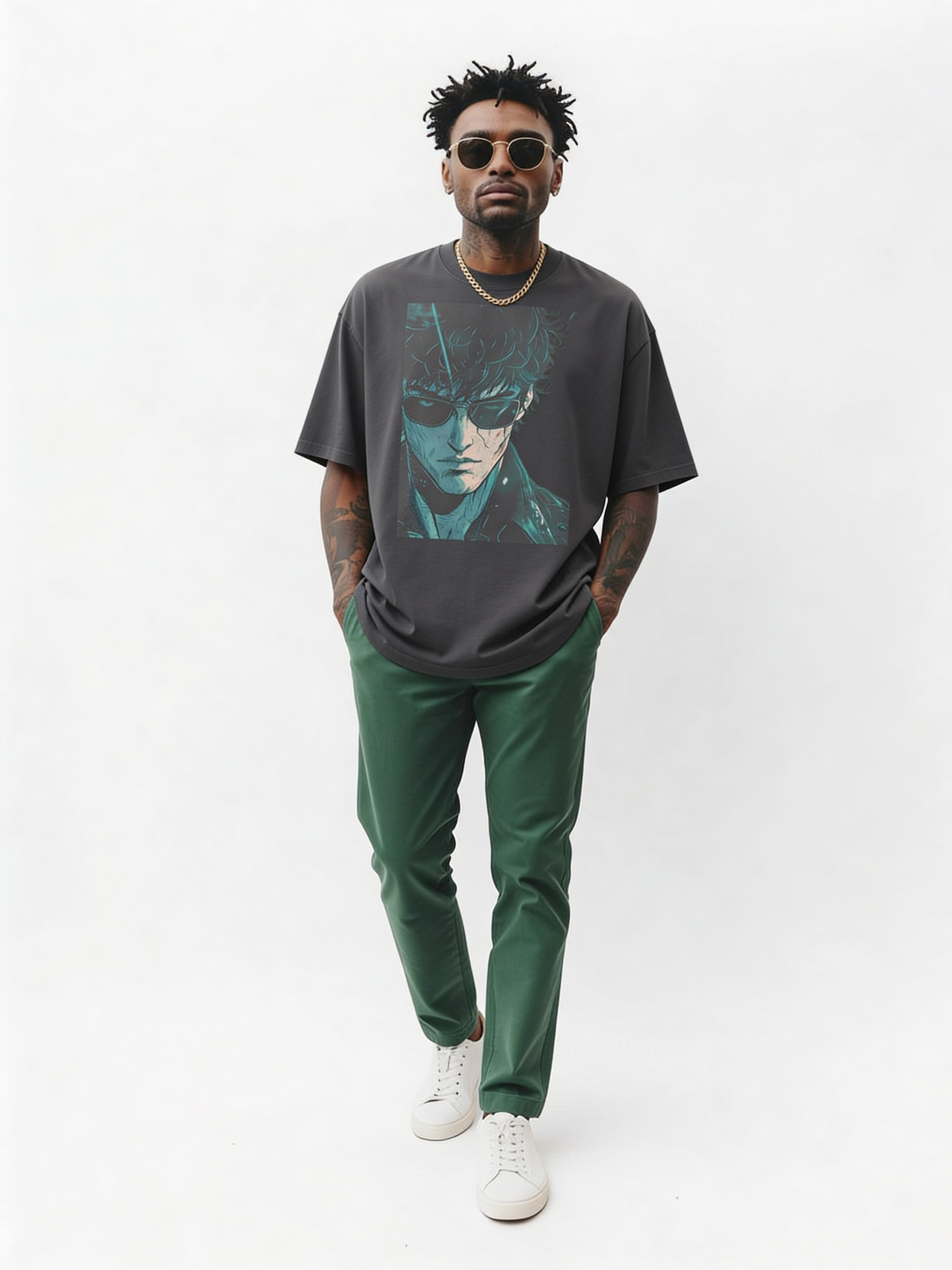 Male model walking in oversized grey graphic t-shirt featuring anime-style portrait print, styled with green trousers and white sneakers in minimalist studio, modern streetwear look