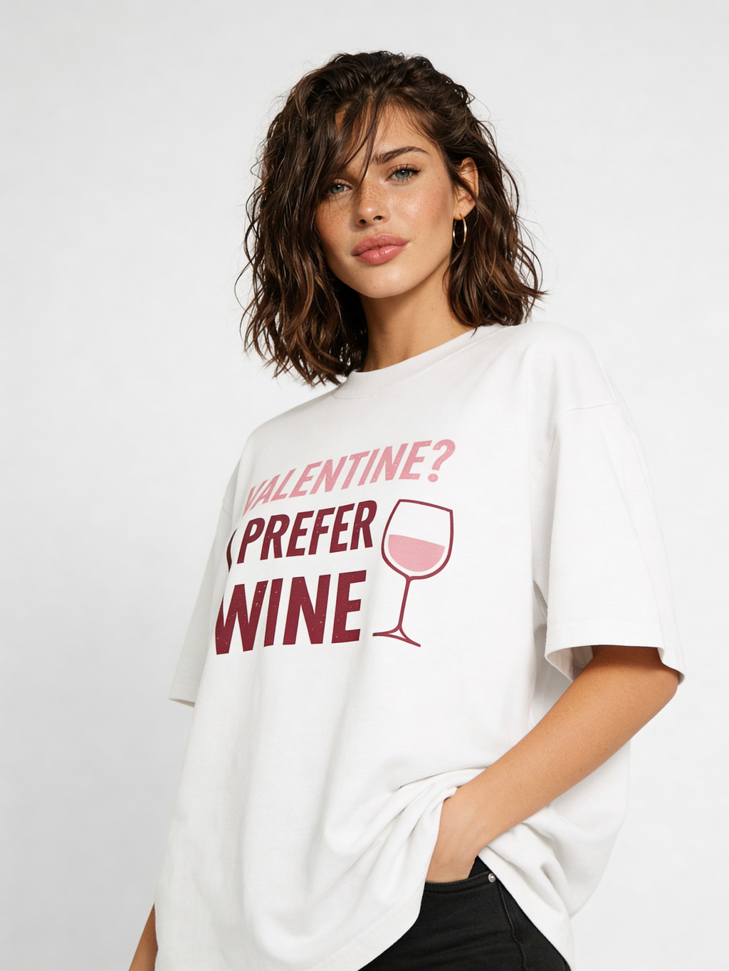 Female fashion model posing in oversized beige Valentine wine quote graphic tee, styled with black jeans for contemporary casual streetwear outfit