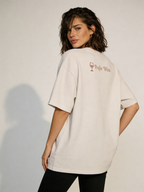 Back view of oversized beige women’s t-shirt with “Prefer Wine” minimalist print and wine glass icon, styled on female model in modern studio