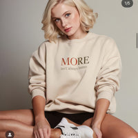 Female model wearing beige oversized heavyweight sweatshirt with “MORE Isn’t Always Better” message, minimalist streetwear look
