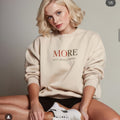 Female model wearing beige oversized heavyweight sweatshirt with “MORE Isn’t Always Better” message, minimalist streetwear look