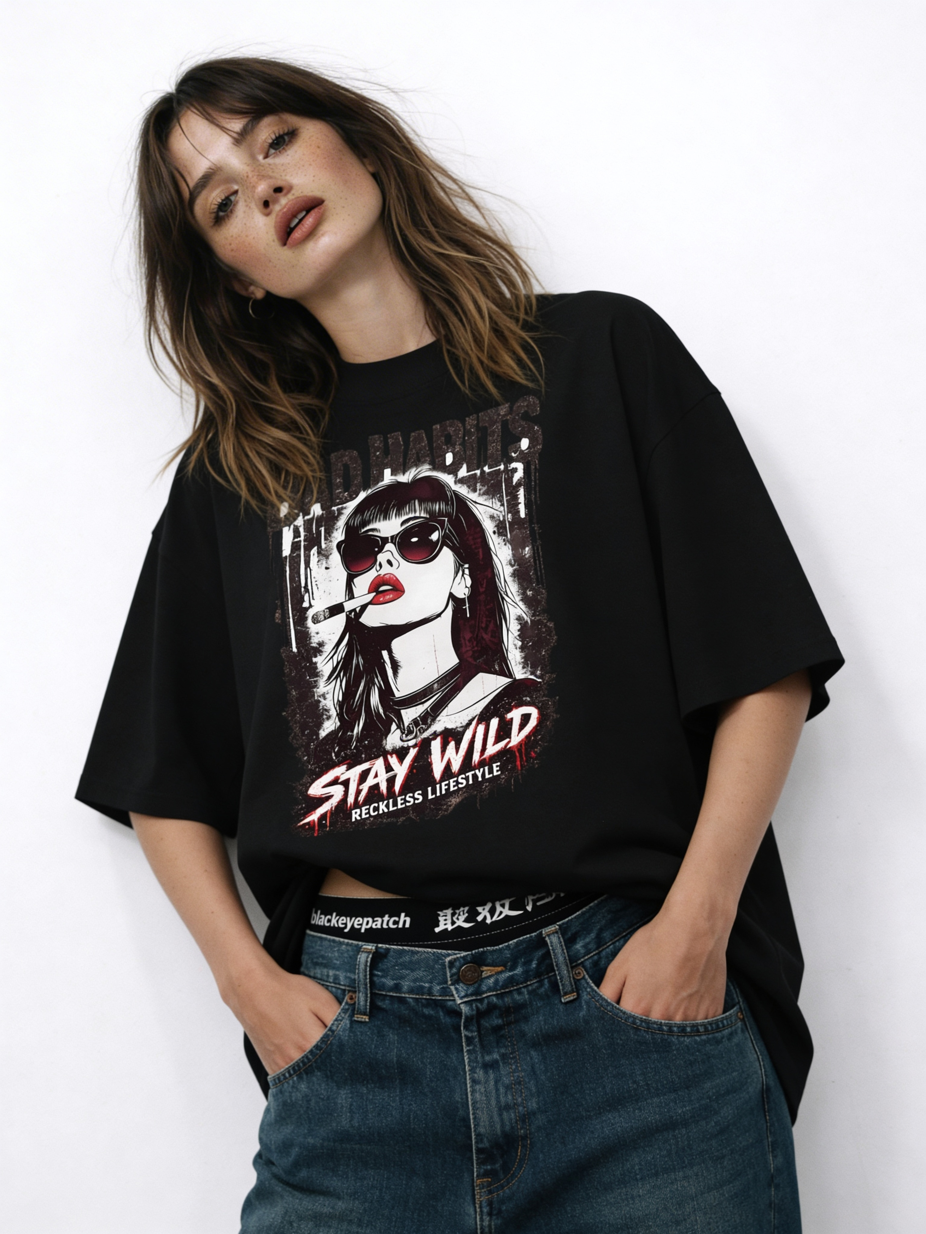 Woman modeling oversized black “Bad Habits Stay Wild” streetwear graphic t-shirt featuring rebellious illustrated portrait and bold red typography