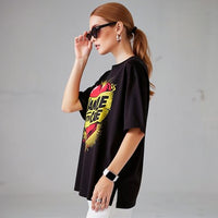 Model wearing black unisex t-shirt with “Handle With Care” heart graphic design in a studio setting