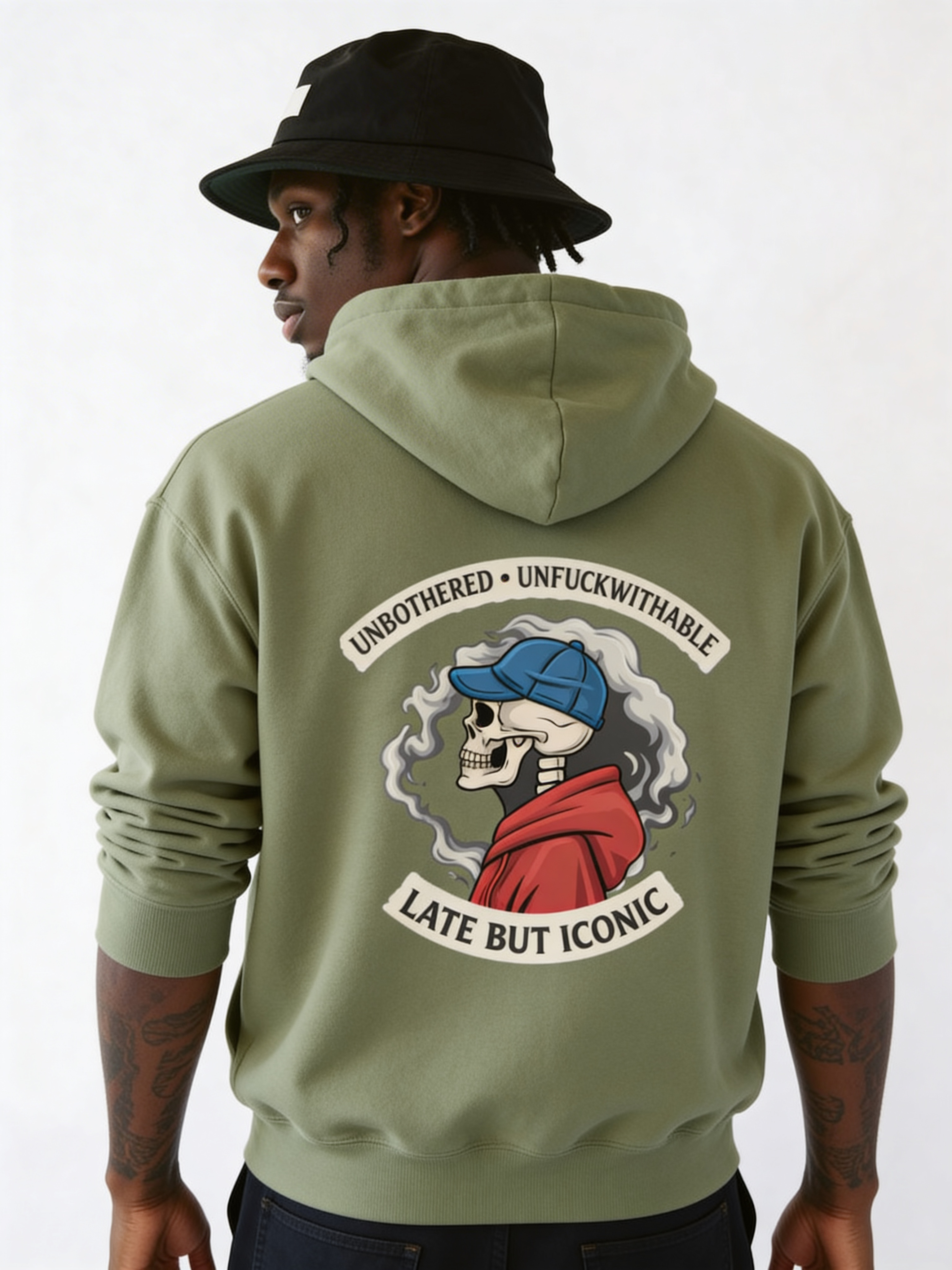 Male model wearing oversized green graphic hoodie with large illustrated back print and vintage emblem design, urban streetwear look