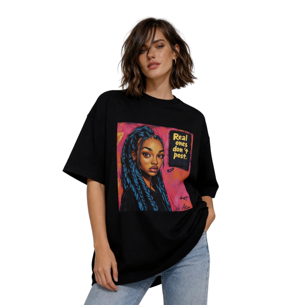 Female model wearing oversized black streetwear T-shirt with “Real ones don’t post” graphic portrait print, paired with light blue jeans.