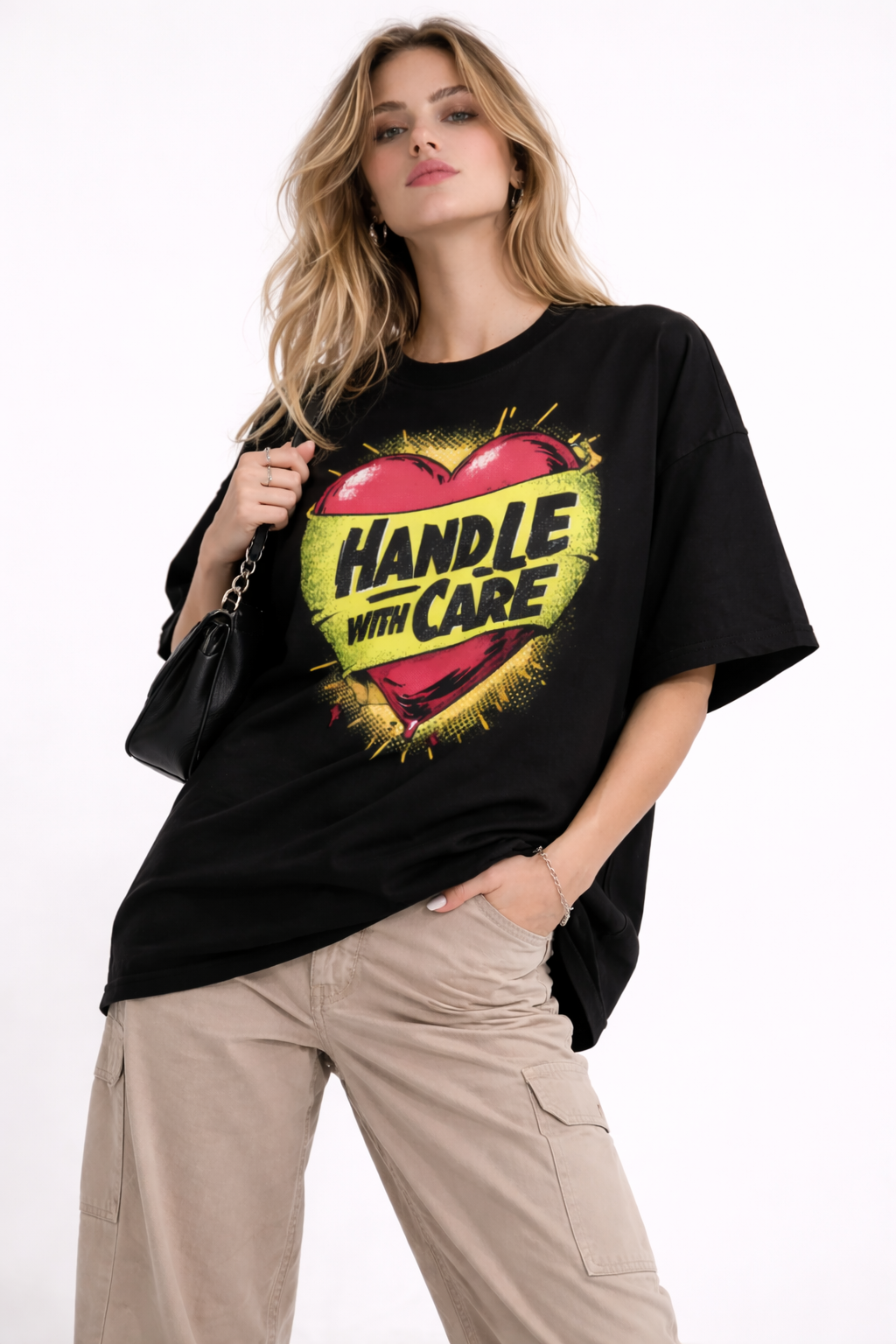 Female model wearing oversized black graphic t-shirt with Handle With Care heart illustration streetwear design