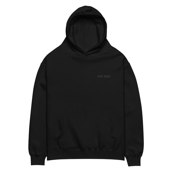 Black oversized unisex hoodie with minimalist front design, featuring subtle “EST. 2025” text on the chest, clean streetwear style and relaxed fit.