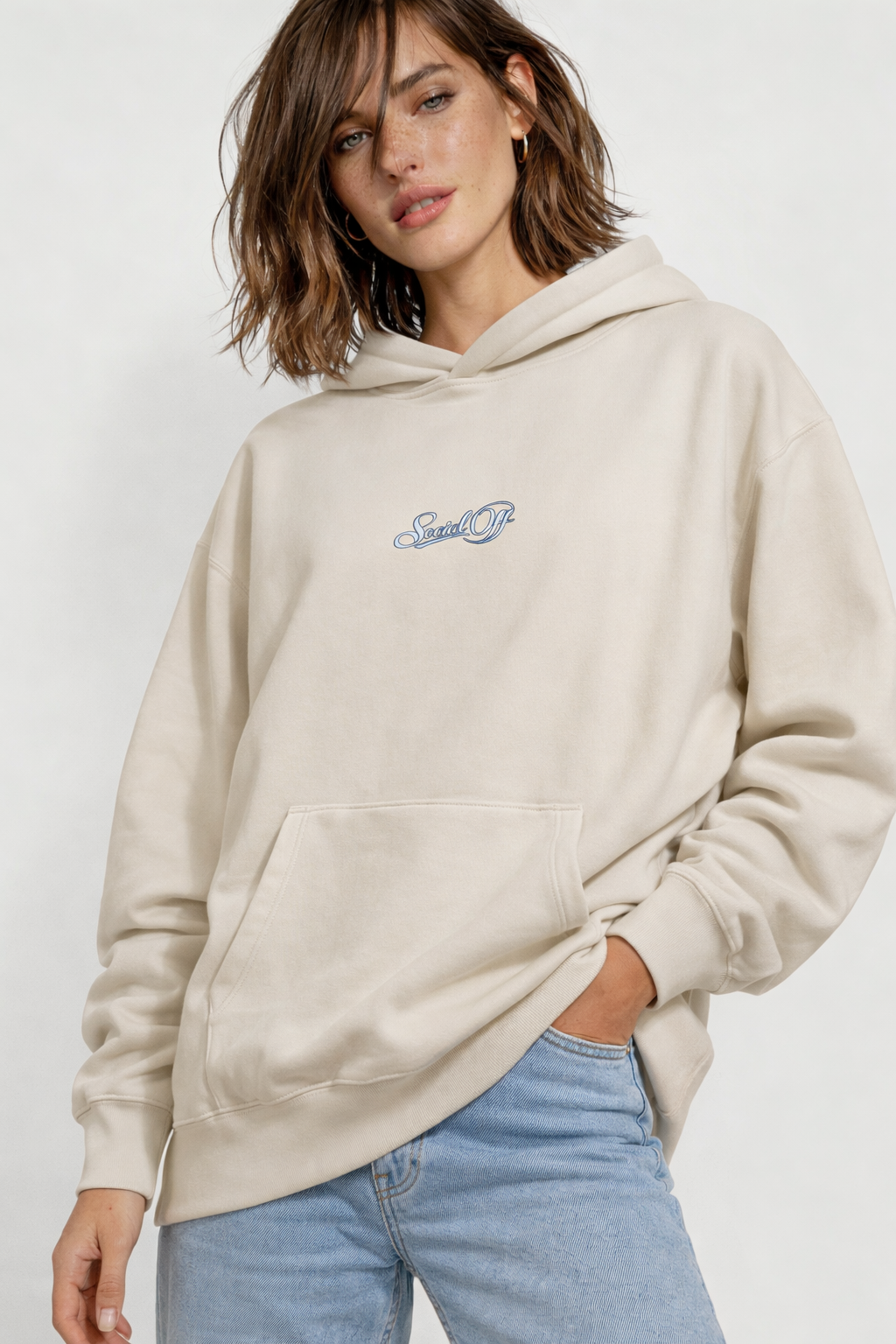 Noiré beige oversized streetwear hoodie front view with minimal “Social Off” script logo print, worn by female model, neutral aesthetic unisex hoodie.