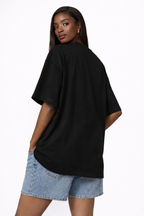 Back view of oversized black urban streetwear graphic t-shirt worn by female model minimalist streetwear outfit