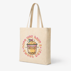 angled product shot beige tote bag kawaii drink illustration soft shadows neutral background e-commerce style