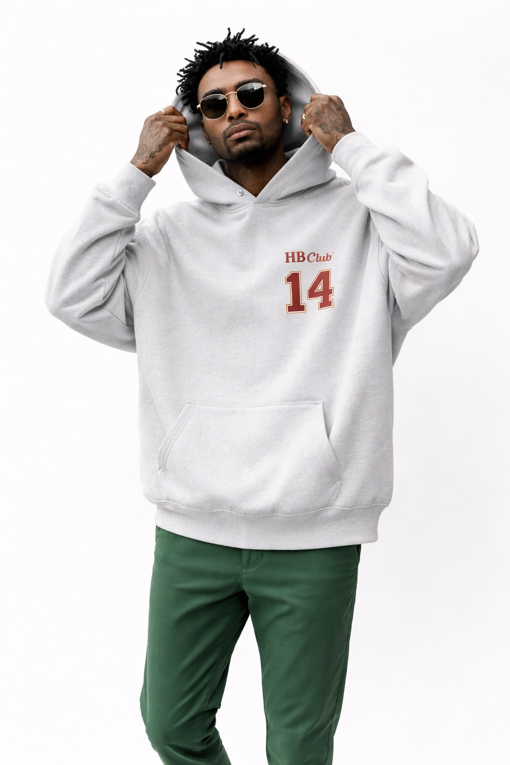 Male model in grey oversized hoodie with small red “14” chest print, casual streetwear look with green trousers.