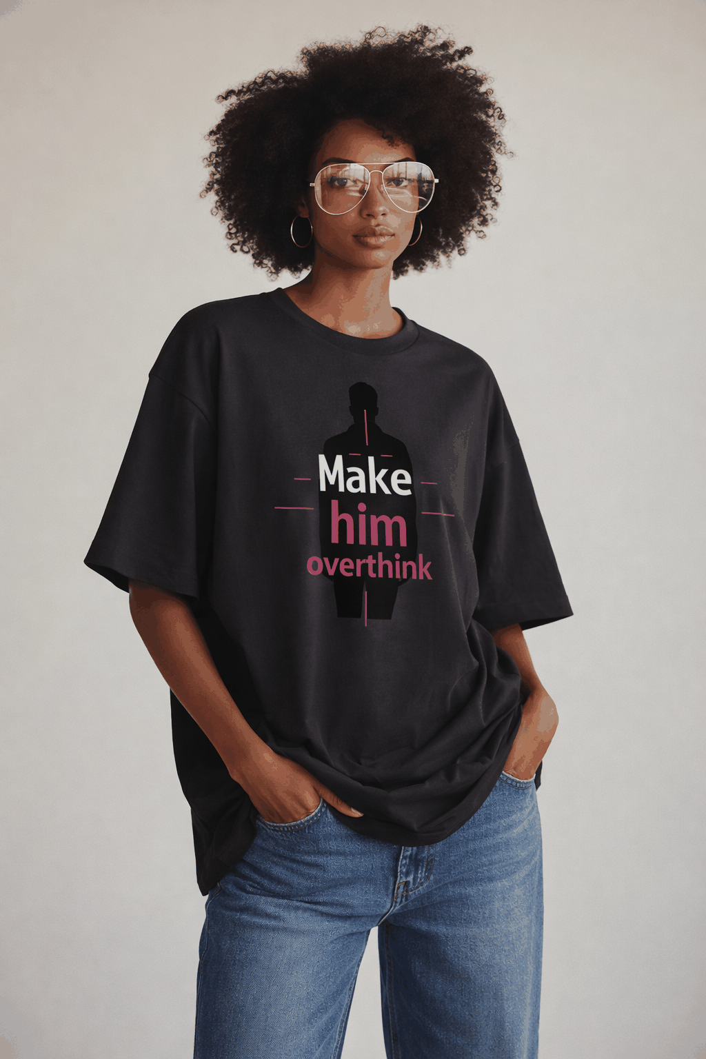 Female model in anthracite oversized “Make him overthink” statement t-shirt with pink graphic print, modern women’s streetwear outfit.