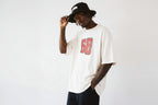 model side pose wearing oversized cream graphic t shirt with red varsity number urban streetwear outfit