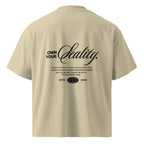 Beige oversized streetwear t-shirt back view with “Own Your Reality” script typography graphic print