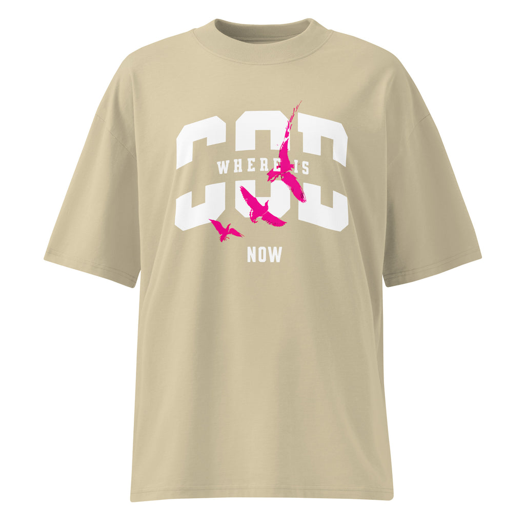 Beige oversized streetwear T-shirt with bold white “GOD” varsity typography, “WHERE IS” text across the center, “NOW” below, and pink bird silhouettes graphic on the front