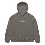 Front view of grey oversized streetwear hoodie with small “Leave Me Alone” chest text print, minimalist unisex casual sweatshirt