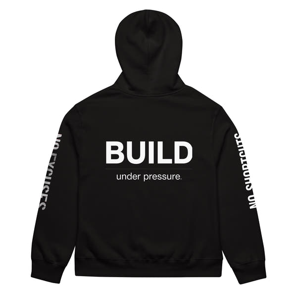 Black unisex oversized hoodie with “Build Under Pressure” statement printed on back, streetwear hoodie back view.