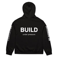 Black unisex oversized hoodie with “Build Under Pressure” statement printed on back, streetwear hoodie back view.