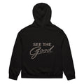 Black unisex streetwear hoodie back view with “See The Good” motivational typography print
